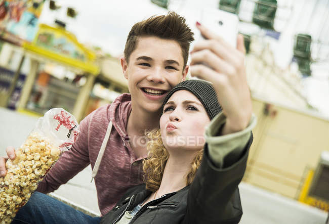 Teenage couple with popcorn taking selfie with smartphone — Stock Photo