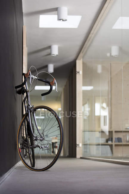 Racing cycle standing in corridor of modern office — Stock Photo