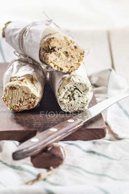 Tre rotoli di burro composto diversamente aromatizzato sul tagliere — Foto stock