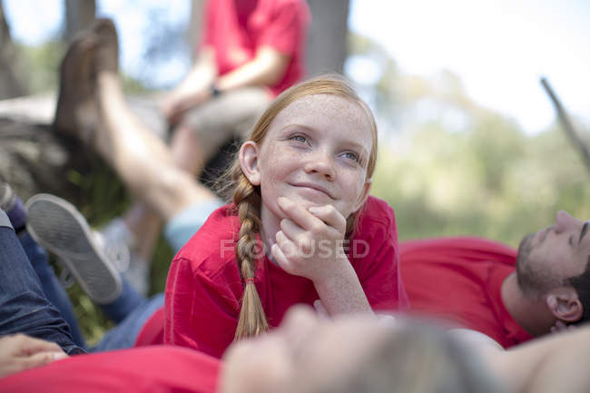 Портрет посміхається дівчина і людей, що лежать на траві — стокове фото