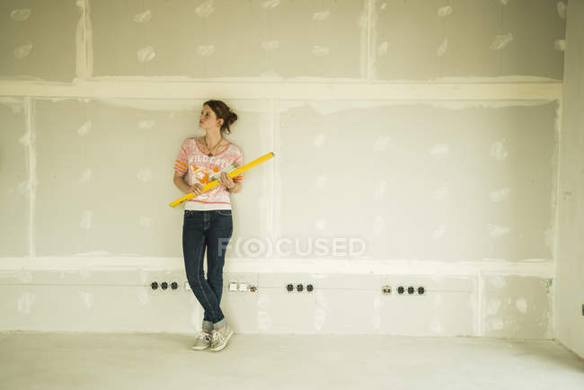 Молода жінка відновлює стоячи біля порожньої стіни — стокове фото