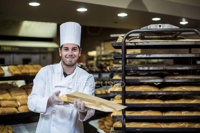 Baker in supermarket packing fresh braed — Stock Photo