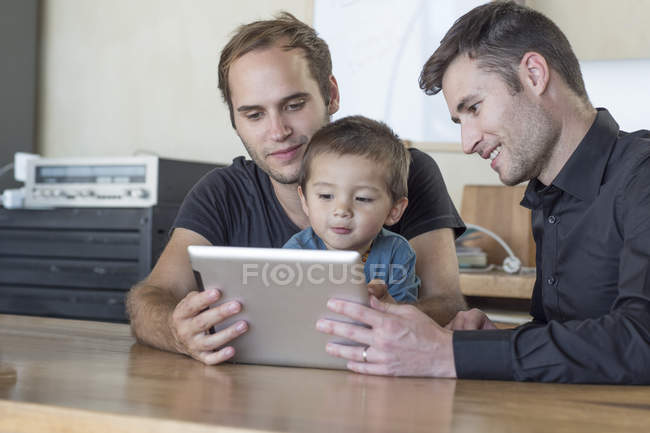 Due uomini con bambino che guardano tablet digitale — Foto stock