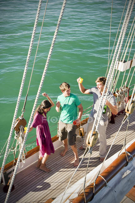 Happy friends drinking and dancing on deck of a sailing ship — Stock Photo