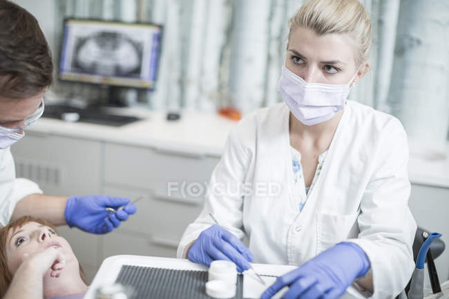 Odontoiatra e assistente che esegue il controllo per il paziente — Foto stock