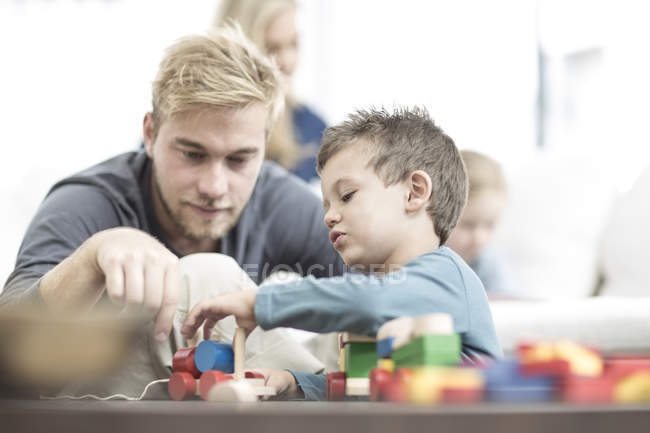 Vater und kleiner Sohn spielen mit Holzspielzeug — Stockfoto