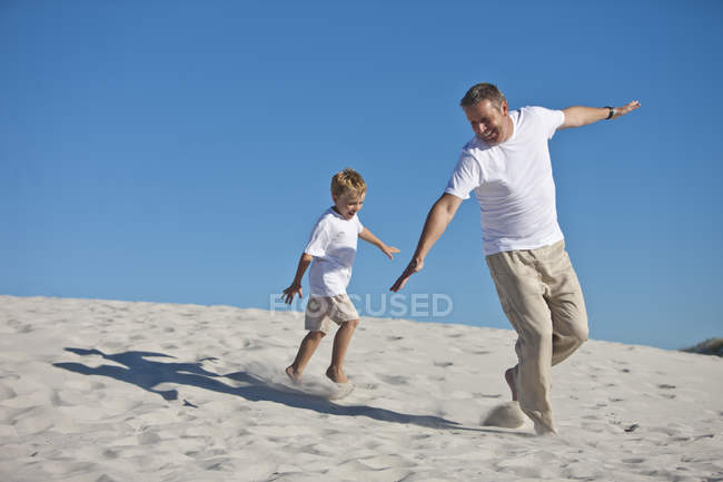 Игривый отец и сын в песке на пляже — стоковое фото