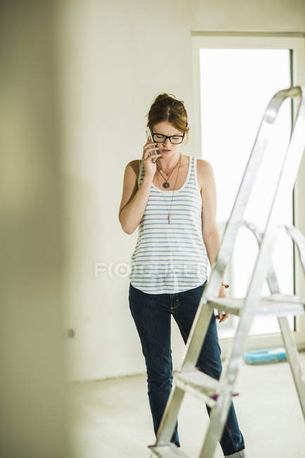 Mujer joven renovando hablando por teléfono celular - foto de stock