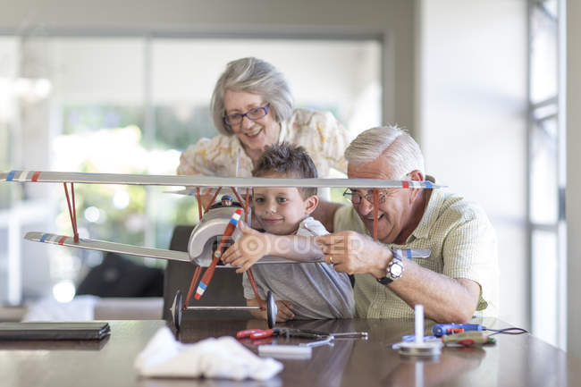 Nonno e nipote costruiscono un aeroplano modello guardato dalla nonna — Foto stock