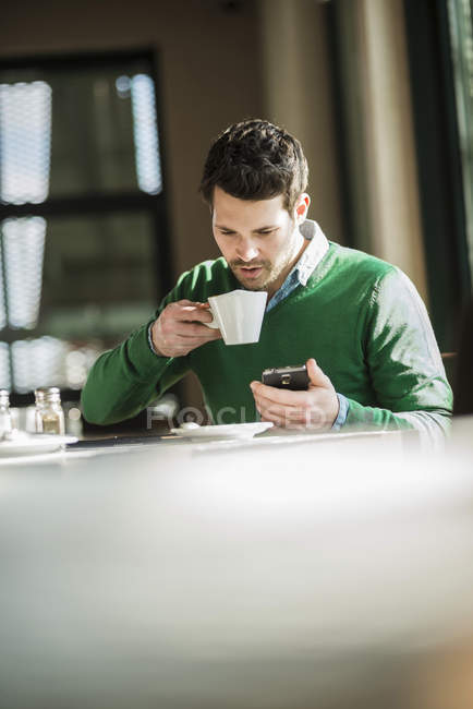 Mann trinkt Kaffee und benutzt Handy — Stockfoto