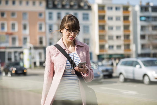 Junge Frau läuft mit Handy auf der Straße — Stockfoto