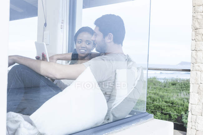 Young couple with digital tablet relaxing in beach house — Stock Photo