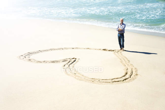 Южная Африка, человек, стоящий перед сердцем вырезанный в песке пляжа — стоковое фото