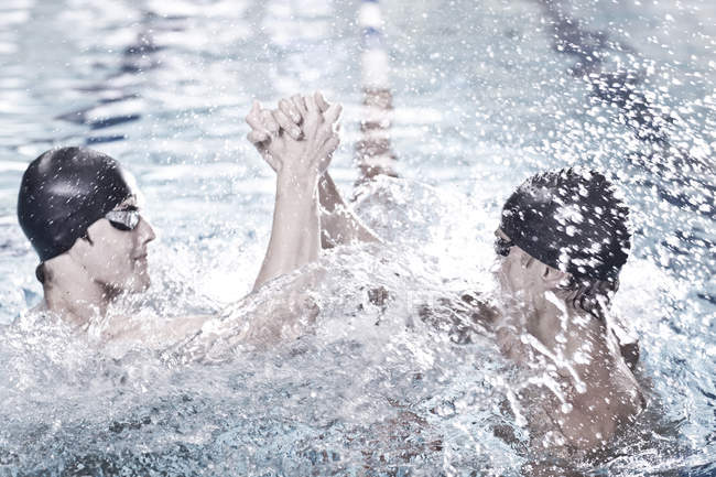 two swimmers relax close together on air mattresses