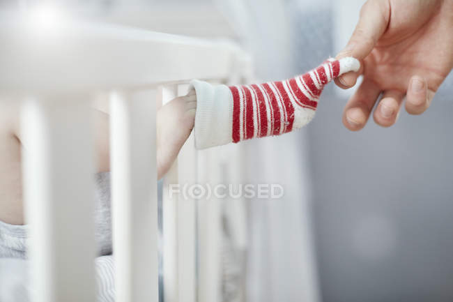 Padre quitando calcetines de bebé en la cuna - foto de stock