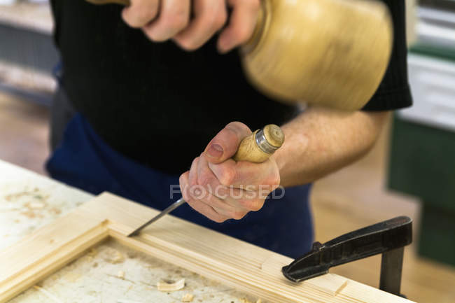 Rahmenbauer arbeitet mit Hammer und Meißel an einem Holzrahmen — Stockfoto