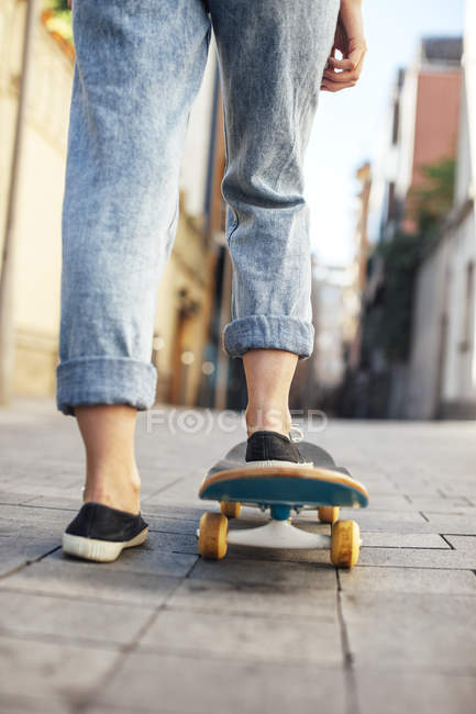 Jeune femme skate boarder sur son skateboard, vue partielle — Photo de stock