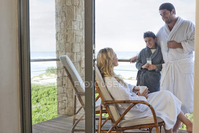 Family wearing bathrobes on patio of beach house — Stock Photo
