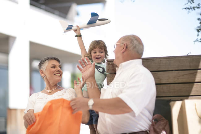 Nonno e nonna regalano al nipote un aeroplano giocattolo — Foto stock