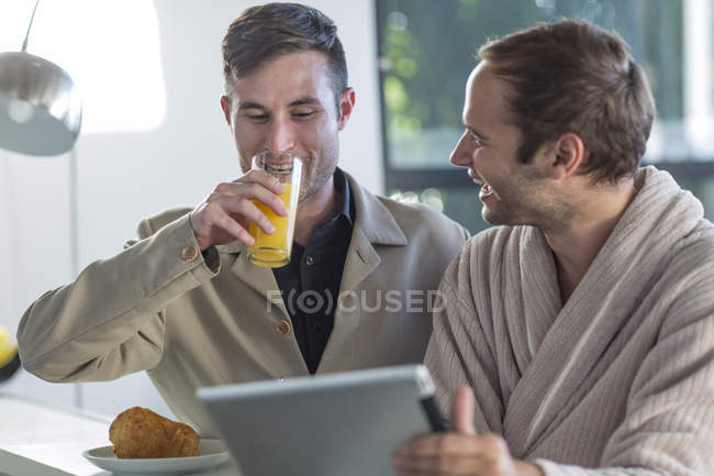 Feliz gay casal usando digital tablet no casa — Fotografia de Stock
