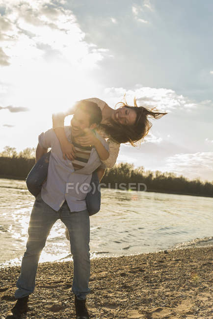 Joyeux jeune couple qui s'amuse au bord de la rivière — Photo de stock