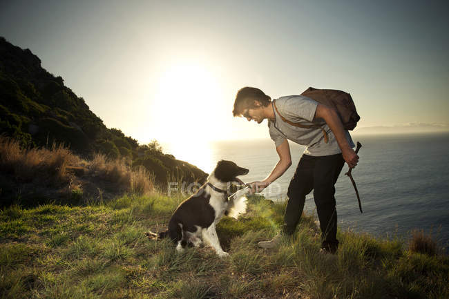 Man with dog at the coast at sunset — Stock Photo