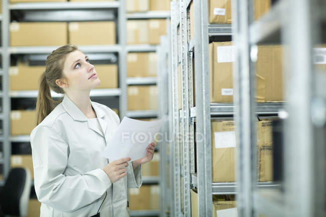 Mujer joven en el almacén mirando hacia arriba - foto de stock