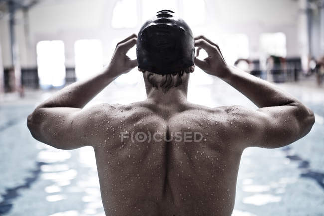 Caucasian swimmer in indoor pool putting on swimmming goggles — Stock Photo