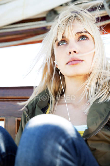 Jeune femme sur un voilier écoutant de la musique — Photo de stock