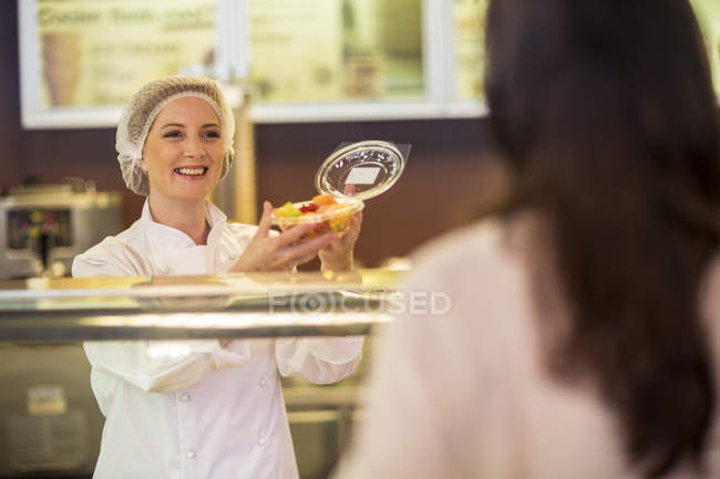 Shop assistant packing fruit salad for customer — Stock Photo