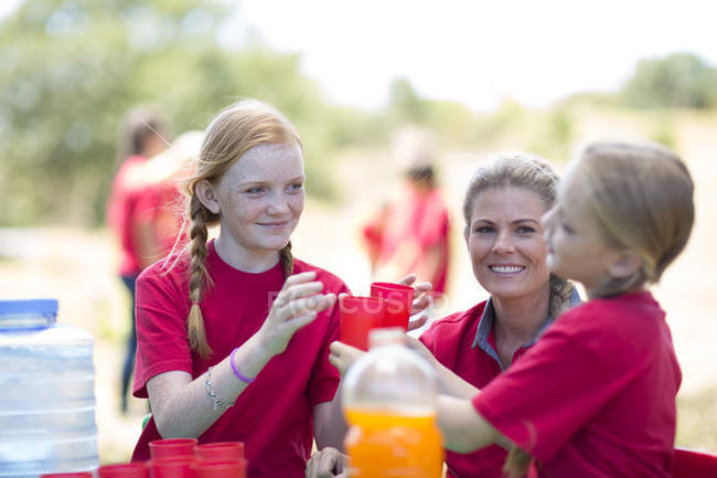 Crianças e mulheres distribuindo bebidas refrescantes — Fotografia de Stock