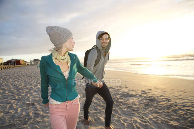 Young couple walking on beach at sunrise — Stock Photo