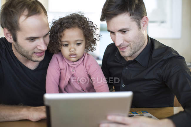 Двое мужчин с ребенком смотрят на цифровой планшет — стоковое фото