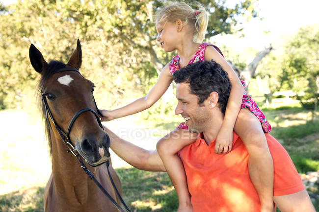 Father and daughter petting a horse — Stock Photo