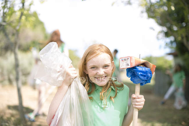 Portrait of smiling girl showing picked up garbage — Stock Photo