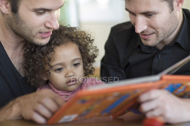 Due uomini con bambino che guardano il libro — Foto stock
