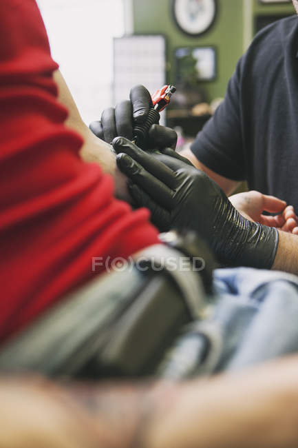 Tatuagem artista fazendo tatuagem para cliente masculino — Fotografia de Stock