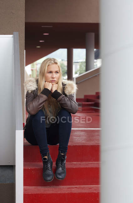 Portrait of sad blond teenage girl sitting on steps — Stock Photo