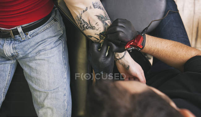 Imagen recortada del artista del tatuaje en el trabajo en el estudio - foto de stock