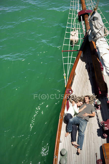 Relaxed mature couple lying on deck of a sailing ship — Stock Photo