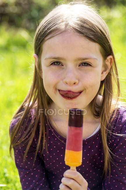 Girl holding ice lolly and licking lips — Stock Photo