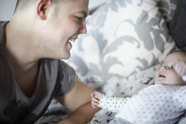 Улыбающийся молодой отец смотрит на ребенка — стоковое фото
