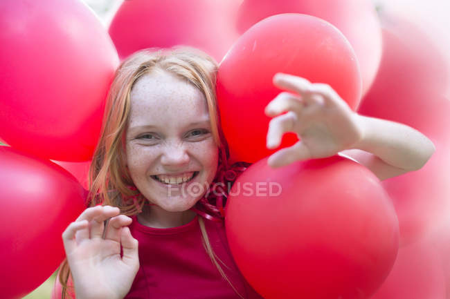 Portrait of smiling girl with red balloons — Stock Photo