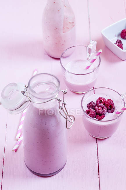 Raspberry smoothie in bottle and in glasses on pink background — Stock Photo