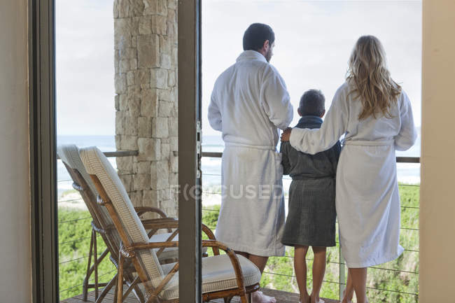 Famiglia in accappatoi in piedi sul patio della casa al mare — Foto stock