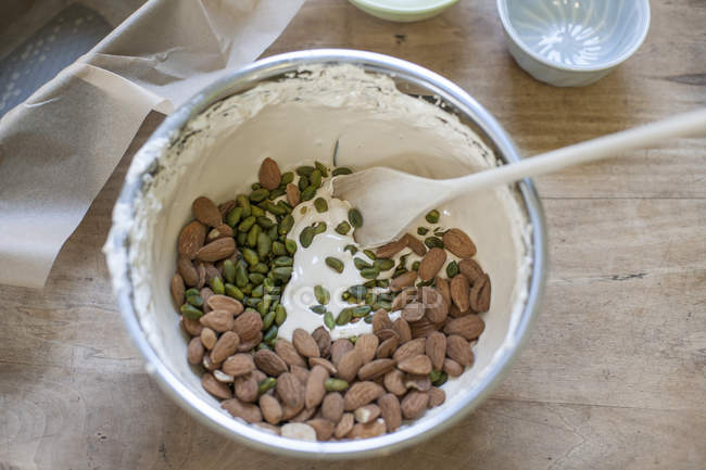 Mixing bowl of almonds, pistachios and beaten egg white, elevated view — Stock Photo