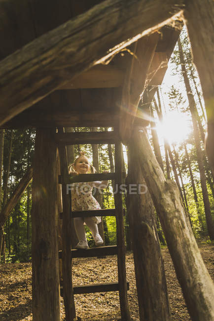 Girl climbing on ladder in forest — Stock Photo