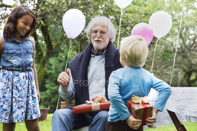 Avô recebendo presentes na festa de aniversário no jardim — Fotografia de Stock