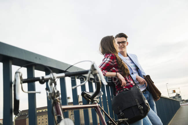 Joven hombre y mujer con bicicleta en el puente - foto de stock