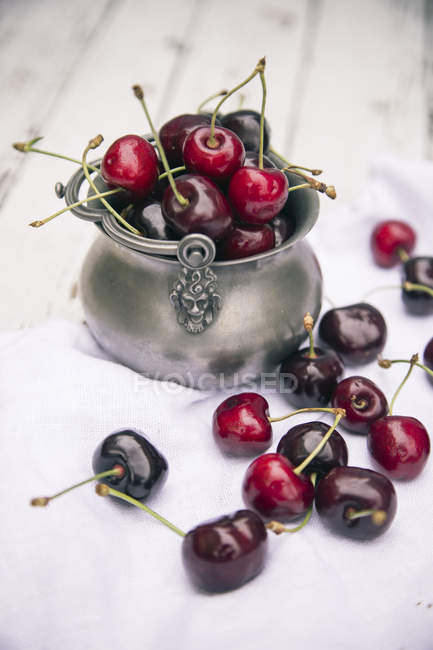 Fresh cherries in bowl on white cloth — Stock Photo